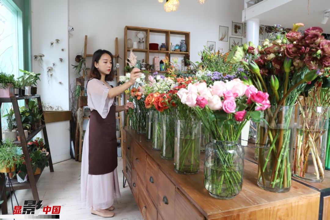 王黎媛是一名河南姑娘，在昆明念完大學(xué)后，就再也舍不下春城的藍(lán)天陽光、青山碧水，更舍不下這里的四時(shí)繁花，于是就干脆留了下來，成了一名媒體人。2017年的時(shí)候又毅然辭去工作，創(chuàng)業(yè)開起了花店，成了都市里的一名“花房姑娘”。圖為王黎媛在自己的花店中整理鮮花。新華網(wǎng) 周亞平/攝 念新洪/文